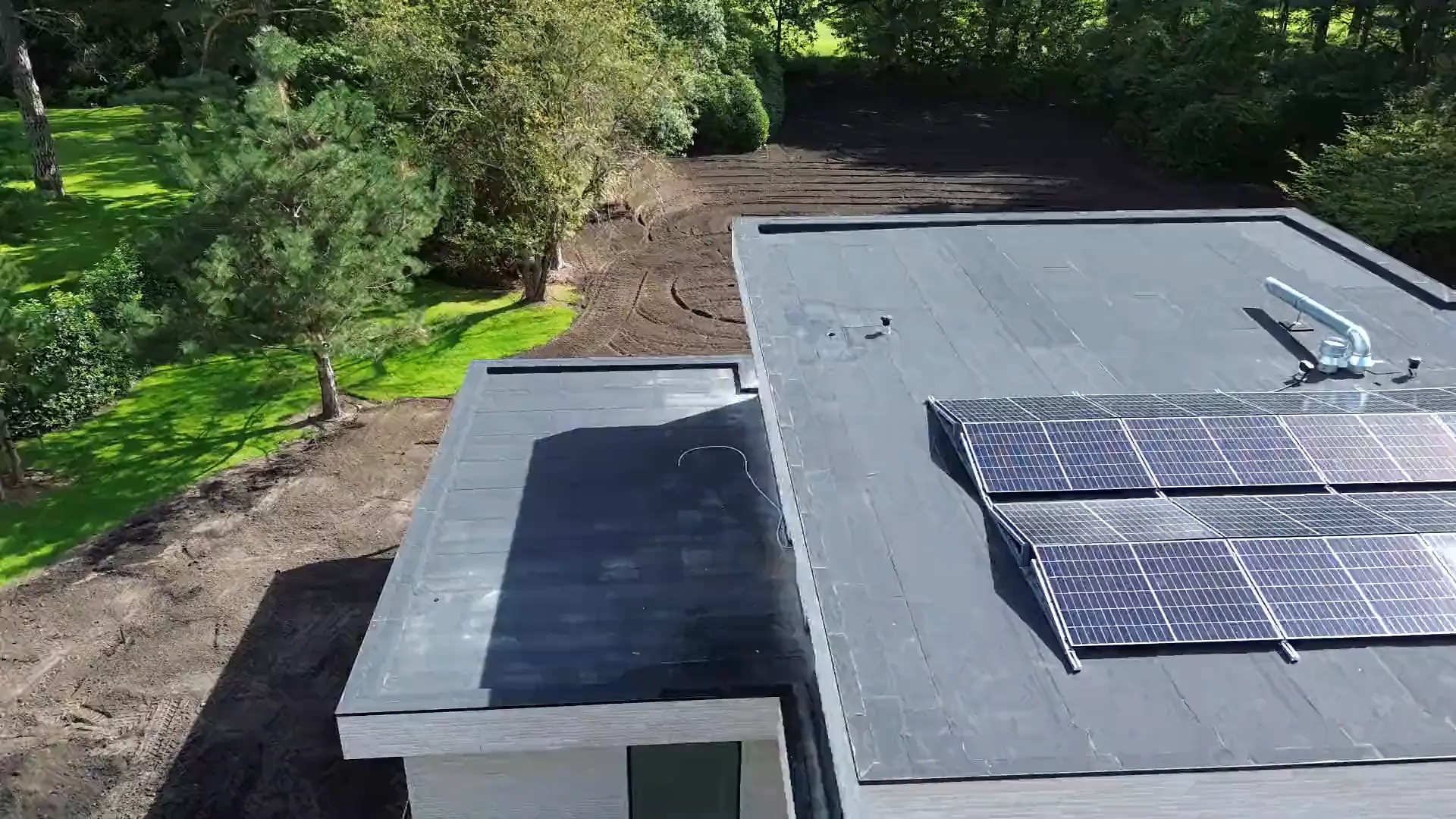 Dronebeeld van een moderne woning met zonnepanelen op het platte dak